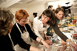 Vier Kochkursteilnehmerinnen in gemeinsamer Aktion an der Arbeitsfl&auml;che