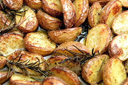 Detail: halbierte kleine Kartoffeln, mit Rosmarinzweigen gebraten